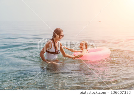 Mother daughter swimming happy parent and young child playing with inflatable ring in the sea on summer vacation 136607353