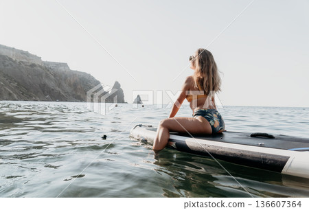 Woman Paddleboard Ocean Relaxation - Woman relaxes on a paddleboard in the ocean. Woman Paddleboard Ocean Relaxation - Woman relaxes on a paddleboard in the ocean. 136607364