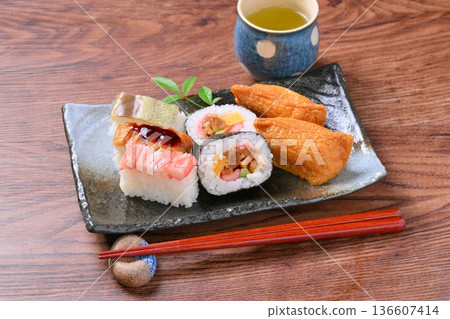 An assortment of inari sushi, inari sushi, thick rolls, and pressed sushi. 136607414