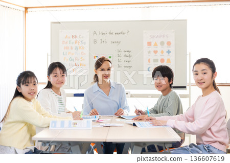 Education: Portrait of a child taking a lesson in an English conversation class and a native teacher Education: Portrait of a child taking a lesson in an English conversation class and a native teacher 136607619