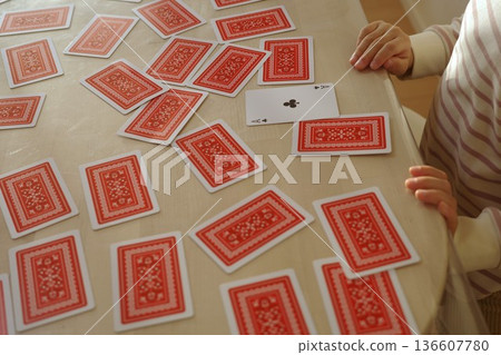 A child turns over the ace of clubs in a deck of cards A child turns over the ace of clubs in a deck of cards 136607780