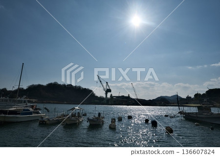 背光照射下的港口和漁船，波光粼粼的海面，還有一台起重機 136607824