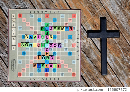 Scrabble Board With Colorful Words Next To A Dark Cross 136607872