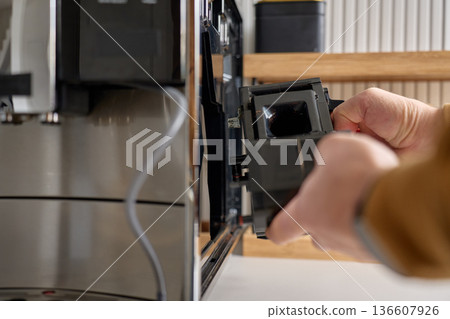 Person taking out internal brew group unit from modern automatic coffee machine. Concept of appliance maintenance, cleaning and home coffee preparation Person taking out internal brew group unit from modern automatic coffee machine. Concept of appliance maintenance, cleaning and home coffee preparation 136607926