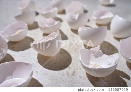 Empty white eggshell halves scattered on light marble surface. Broken chicken eggs on kitchen countertop. Concept of food waste, cooking preparation and biodegradable kitchen leftovers Empty white eggshell halves scattered on light marble surface. Broken chicken eggs on kitchen countertop. Concept of food waste, cooking preparation and biodegradable kitchen leftovers 136607929