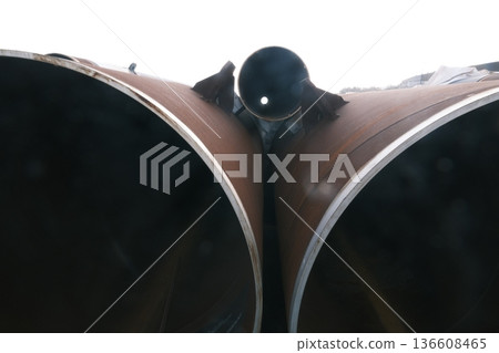 A symmetrical composition of a giant steel pipe floating in the backlight A symmetrical composition of a giant steel pipe floating in the backlight 136608465