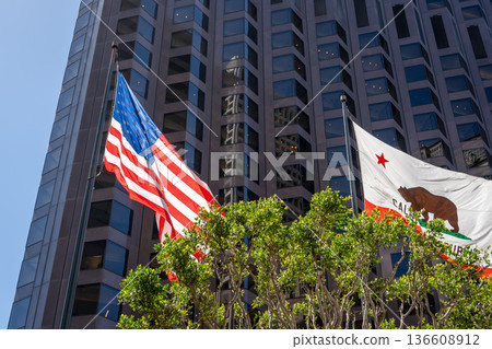 American and California flags waving in front of a modern building 136608912