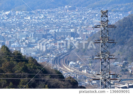 一列火車穿梭於山脈之間,從半山腰的高壓塔上可俯瞰城市景觀。 一列火車穿梭於山脈之間,從半山腰的高壓塔上可俯瞰城市景觀。 136609091