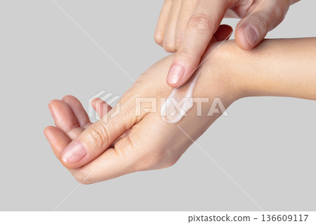 Close up photo woman hands with a white swatch sampled with a smear of cream. Self-care concept, skin care, hand care, facial care. Isolated gray background photo Close up photo woman hands with a white swatch sampled with a smear of cream. Self-care concept, skin care, hand care, facial care. Isolated gray background photo 136609117