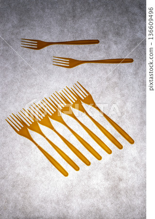 Yellow plastic forks on a gray background Yellow plastic forks on a gray background 136609496