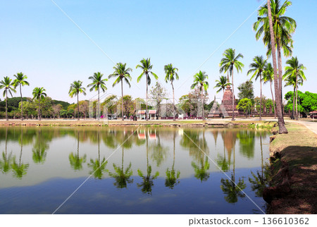 Ancient chedi and palms near pond, Sukhothai historical park, Thailand. Picturesque landscape with stone stupa in Sukhothai old city, Northern Thailand. Topic of vacation, travel, trip, cruise, tour Ancient chedi and palms near pond, Sukhothai historical park, Thailand. Picturesque landscape with stone stupa in Sukhothai old city, Northern Thailand. Topic of vacation, travel, trip, cruise, tour 136610362