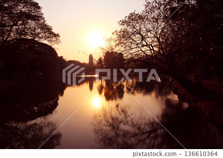 Sunset scene in Ayutthaya Historical Park, Thailand. Picturesque scene with old temple, rivet and trees, Ayutthaya old city. Topic of vacation, travel, trip, cruise, tour. Photo toned in yellow color Sunset scene in Ayutthaya Historical Park, Thailand. Picturesque scene with old temple, rivet and trees, Ayutthaya old city. Topic of vacation, travel, trip, cruise, tour. Photo toned in yellow color 136610364