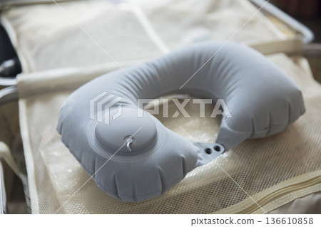 An air pump neck pillow placed on top of a suitcase 136610858