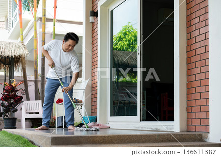A man mops the floor at home on a calm morning, keeping his space neat and tidy. The simple routine reflects awareness and responsibility. A man mops the floor at home on a calm morning, keeping his space neat and tidy. The simple routine reflects awareness and responsibility. 136611387