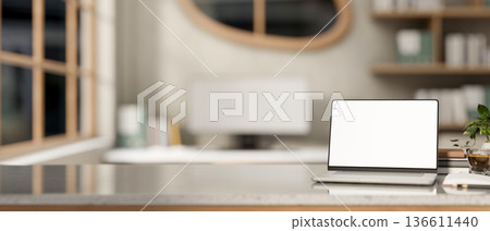 White screen laptop aside books and coffee on marble table across window and computer in living room 136611440