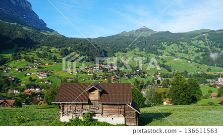 Traditional Schale-style houses dot the lush slopes of the Swiss Alps and mountain scenery Traditional Schale-style houses dot the lush slopes of the Swiss Alps and mountain scenery 136611563
