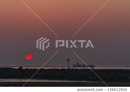 A bright red sunset and cargo ship in Hamaatsuma, Hokkaido, Pacific Ocean A bright red sunset and cargo ship in Hamaatsuma, Hokkaido, Pacific Ocean 136612920