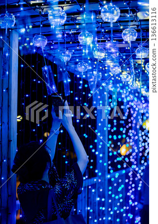 【愛知縣飛島村】在飛島夕陽燈節，一位女士用智慧型手機拍攝壯觀的風鈴和燈光秀。 136613116