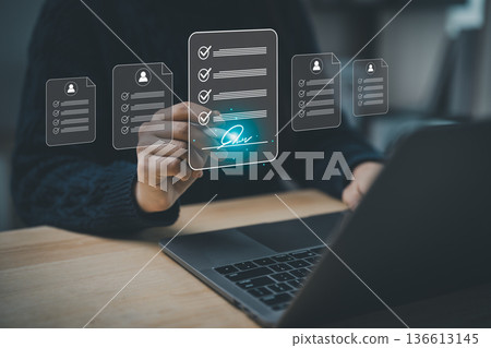 Person reviewing digital checklists on computer screen with transparent icons, demonstrating modern technology and productivity in workspace setting 136613145