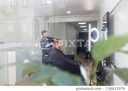 Barbershop professional cutting client s hair from outside view 136613374