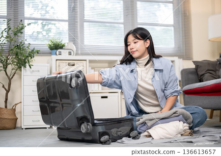Asian woman opening her luggage organize or packing while sitting on bedroom or living room's floor Asian woman opening her luggage organize or packing while sitting on bedroom or living room's floor 136613657