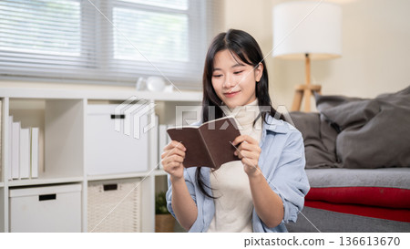 Asian woman holding passport while organizing or packing a luggage on bedroom or living room's floor Asian woman holding passport while organizing or packing a luggage on bedroom or living room's floor 136613670
