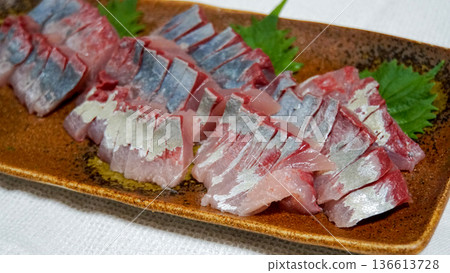 新鮮稻田刺身盛於陶瓷盤中,佐以紫蘇葉。 新鮮稻田刺身盛於陶瓷盤中,佐以紫蘇葉。 136613728