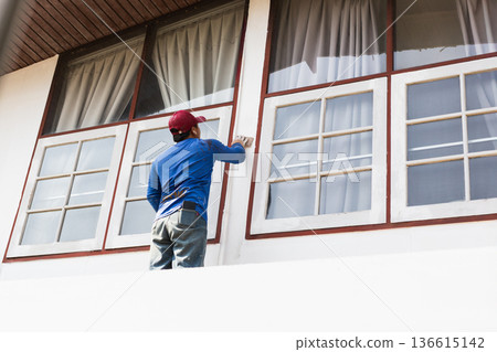 Construction worker sanding and preparing exterior of a residential building. Construction worker sanding and preparing exterior of a residential building. 136615142
