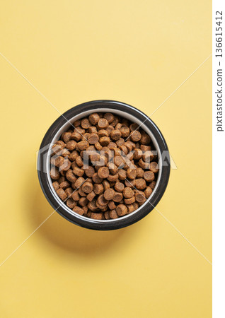 A bowl of dry dog food on a yellow isolated background A bowl of dry dog food on a yellow isolated background 136615412