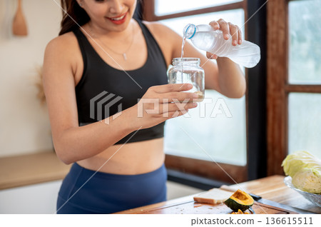 Asian woman adding pouring water in jar making protein powder shake drink at kitchen cooking counter Asian woman adding pouring water in jar making protein powder shake drink at kitchen cooking counter 136615511