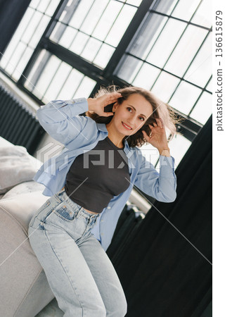 Cheerful Woman Posing on Couch Near Big Window 136615879