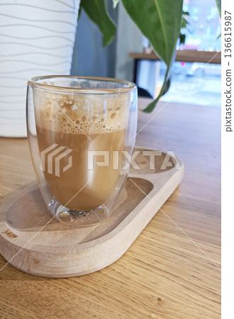 Glass coffee cup held in a wooden table. Coffee brand presentations, or eco-conscious packaging mockups, organic environment. Glass coffee cup held in a wooden table. Coffee brand presentations, or eco-conscious packaging mockups, organic environment. 136615987