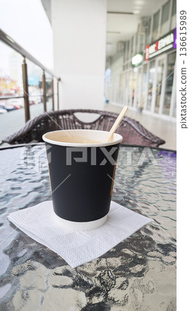 Black coffee cup held in a glass table. Coffee brand presentations, or eco-conscious packaging mockups, organic environment. Black coffee cup held in a glass table. Coffee brand presentations, or eco-conscious packaging mockups, organic environment. 136615989