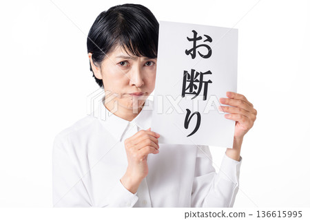 一位身穿白襯衫的老婦人拿著一張寫著「不」的紙，嘟著嘴 136615995
