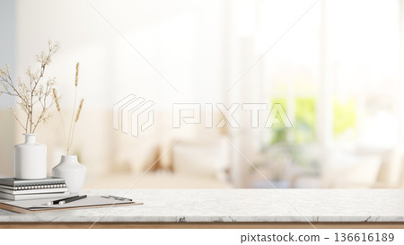 Pencil on clipboard and flower vase over book on marble counter table in blurred bright living room. Pencil on clipboard and flower vase over book on marble counter table in blurred bright living room. 136616189