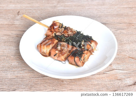 grilled white tofu wrapped pork bacon stabbing in wooden stick topping dry seaweed and fish dressing soy sauce on plate 136617269