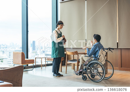A restaurant employee serving a man in a wheelchair 136618076