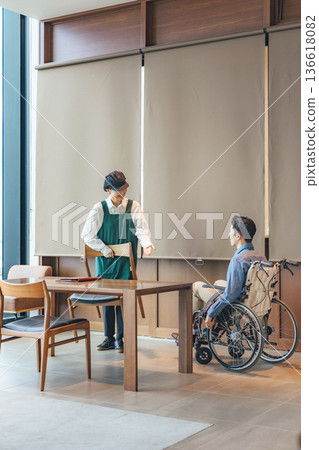一名餐廳員工為一位坐輪椅的男士服務 一名餐廳員工為一位坐輪椅的男士服務 136618082