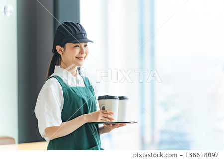 Smiling restaurant employee holding a paper cup Smiling restaurant employee holding a paper cup 136618092