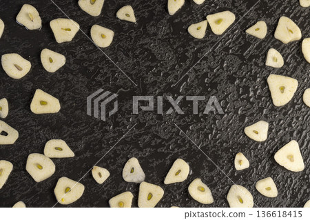 freshly peeled and sliced garlic cloves scattered on black slate, peeled and sliced fragrant and fresh spices from garlic cloves scattered on black slate stone, covered with drops of water freshly peeled and sliced garlic cloves scattered on black slate, peeled and sliced fragrant and fresh spices from garlic cloves scattered on black slate stone, covered with drops of water 136618415