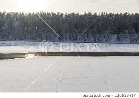 a wide river that is frozen in winter after frosts, a small part of the river that is not frozen after severe frosts, the rest of the river is covered with ice and fresh snow a wide river that is frozen in winter after frosts, a small part of the river that is not frozen after severe frosts, the rest of the river is covered with ice and fresh snow 136618417