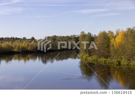 autumn river at sunset, beautiful deciduous trees on the riverbank before the fall of leaves, evening time before sunset autumn river at sunset, beautiful deciduous trees on the riverbank before the fall of leaves, evening time before sunset 136618418