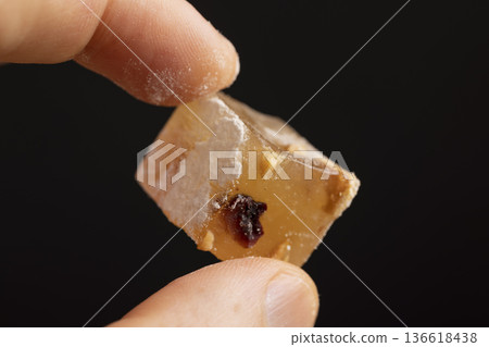 hold a soft and fresh Turkish delight sprinkled with a small amount of powdered white sugar, cubic sweet white soft pieces of Turkish delight with nuts and fruits, hold sweetness in hands 136618438