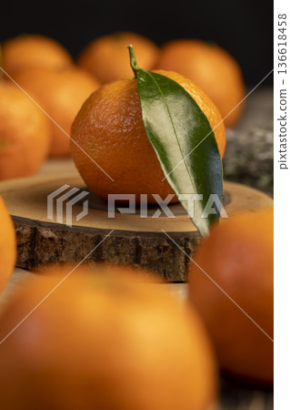 orange small tangerines with green leaves on a wooden board and crumpled yellow paper, a group of ripe sweet tangerines with green leaves in the kitchen orange small tangerines with green leaves on a wooden board and crumpled yellow paper, a group of ripe sweet tangerines with green leaves in the kitchen 136618458