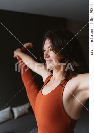 Woman Smiling While Stretching in Orange Outfit Woman Smiling While Stretching in Orange Outfit 136619006
