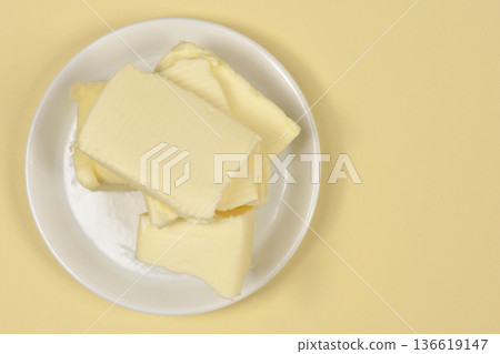 Slices of fresh butter on a white plate 136619147