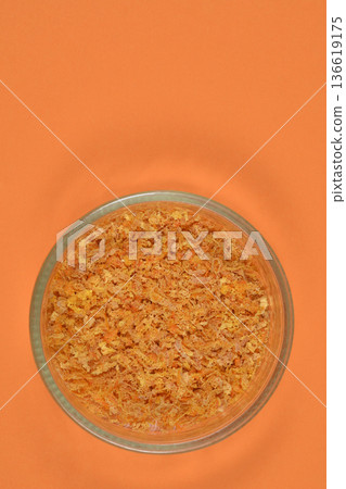 Dried orange peel in a glass bowl on orange background Dried orange peel in a glass bowl on orange background 136619175