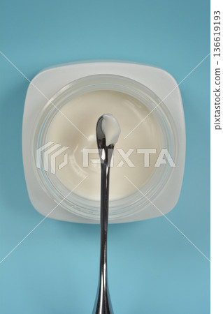 Face cream in a jar with cosmetic spatula on blue background Face cream in a jar with cosmetic spatula on blue background 136619193
