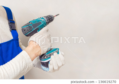 A man is holding a power drill, wearing gloves. A man is holding a power drill, wearing gloves. 136619270