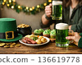 Friends toasting with green ale for Saint Patricks Day. Festive table with corned beef, cupcakes and lucky charms. 136619778